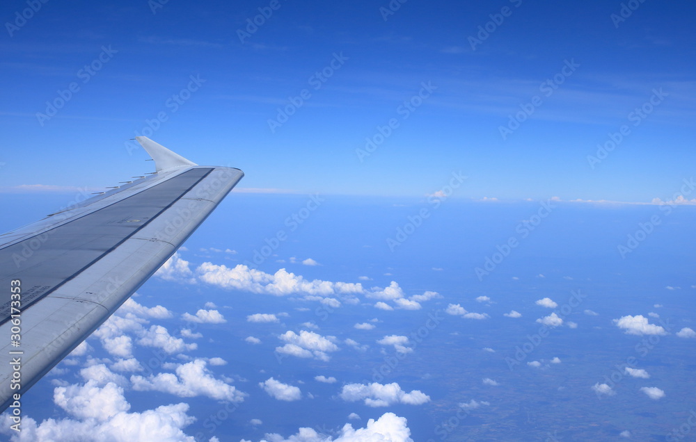 Fototapeta premium Airplane wing on the blue sky and clouds, View from window of plane.