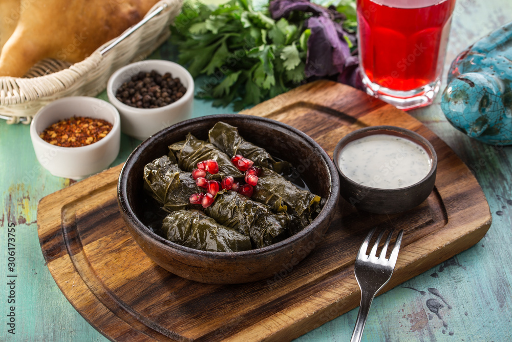 plate of delicious stuffed grape leaves with ground meat and pomegranate on wooden board plate of delicious stuffed grape leaves with ground meat and pomegranate on wooden board