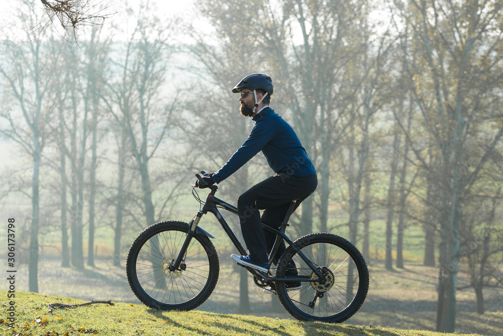 Cyclist in pants and fleece jacket on a modern carbon hardtail bike with an air suspension fork. The guy on the top of the hill rides a bike.