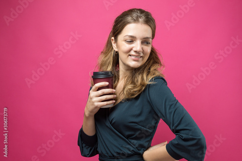 Glamor woman in glasses in a blue sweater with a drink of coffee on a pink background. 