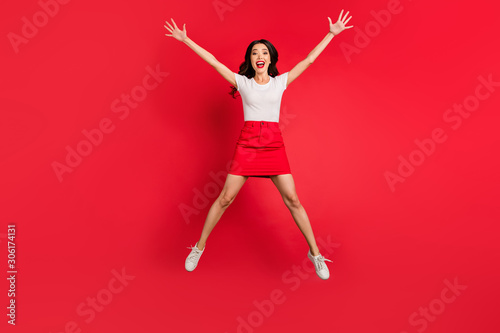 Full length body size view of nice attractive lovely pretty overjoyed cheerful cheery slim fit wavy-haired girl jumping having fun time isolated over bright vivid shine vibrant red color background