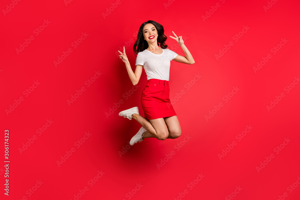Full length body size view of nice attractive lovely cheerful cheery slim fit thin wavy-haired girl jumping showing v-sign having fun isolated over bright vivid shine vibrant red color background