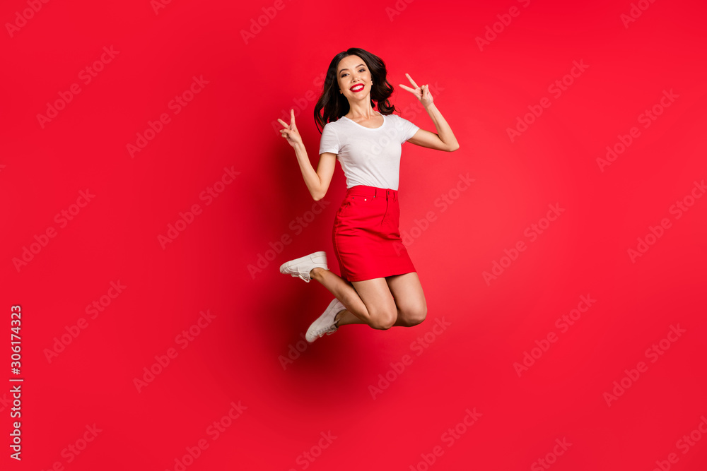 Full length body size view of nice attractive lovely cheerful cheery slim fit thin wavy-haired girl jumping showing v-sign having fun isolated over bright vivid shine vibrant red color background Full length body size view of nice attractive lovely cheerful cheery slim fit thin wavy-haired girl jumping showing v-sign having fun isolated over bright vivid shine vibrant red color background