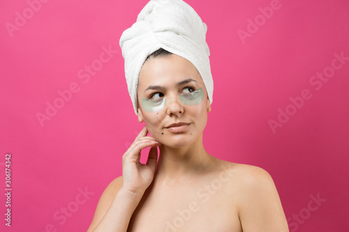 Young beautiful girl in a white towel on his head wears collagen gel patches under her eyes. Mask under eyes treatment face.