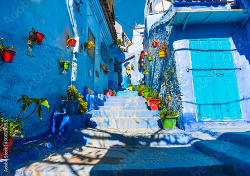Chefchaouen street in Morocco with blue walls and colorful flowerpots © leelook