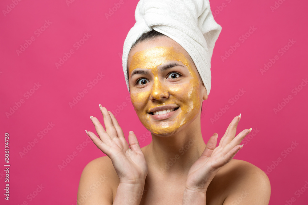 Beauty portrait of woman in white towel on head with gold nourishing mask on face. Skincare cleansing eco organic cosmetic spa relax concept. Beauty portrait of woman in white towel on head with gold nourishing mask on face. Skincare cleansing eco organic cosmetic spa relax concept.