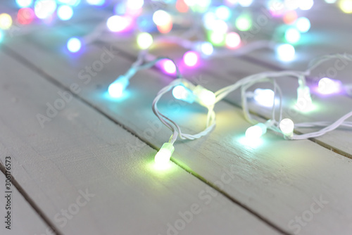 Christmas tree lights or fairy lights over festive white wooden board background with copy space