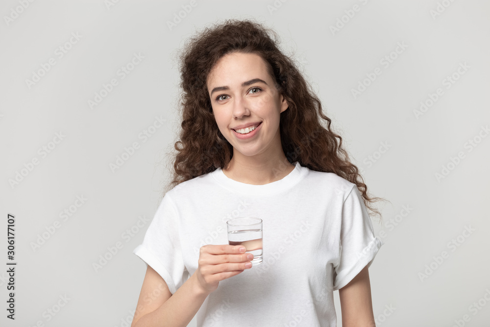 Smiling young female look at camera holding pure water glass Smiling young female look at camera holding pure water glass