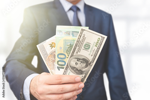 Man in a suit holds different currencies