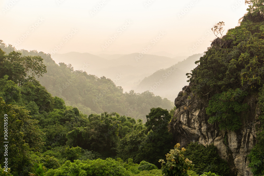 Beautiful mountain landscape with sunset. View of foggy hills covered by forest.