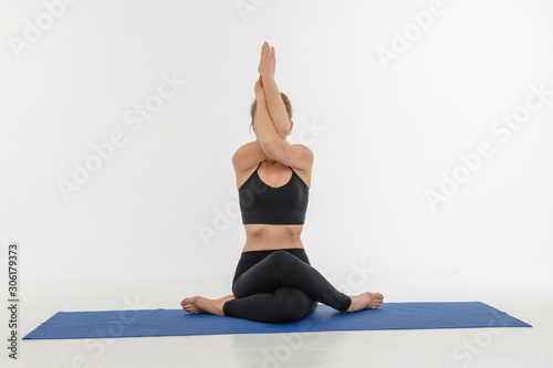 Sporty attractive young woman doing yoga practice on white background. Gomukhasana