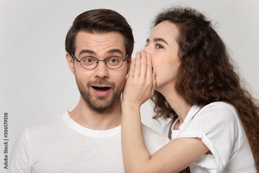 Millennial girl whisper secret in amazed boyfriend ear Millennial girl whisper secret in amazed boyfriend ear