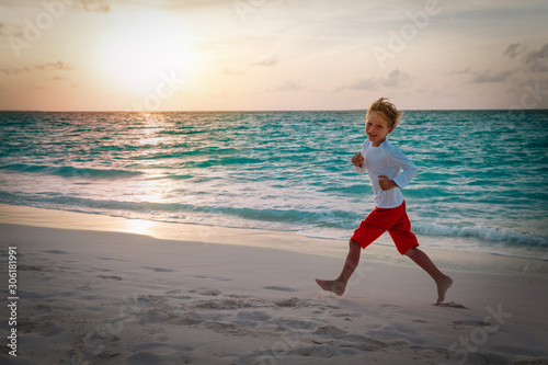 happy little boy run and play at sunset beach