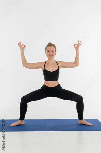Sporty attractive young woman doing yoga practice on white background.