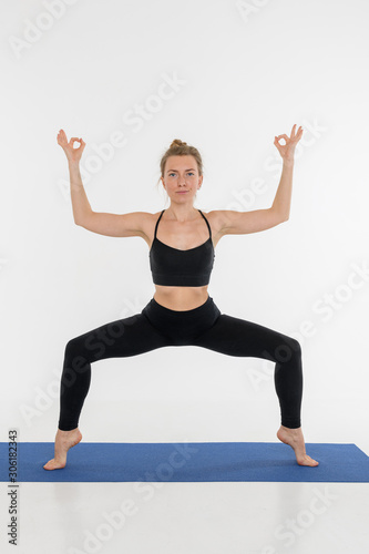 Sporty attractive young woman doing yoga practice on white background. © Alexey Seafarer