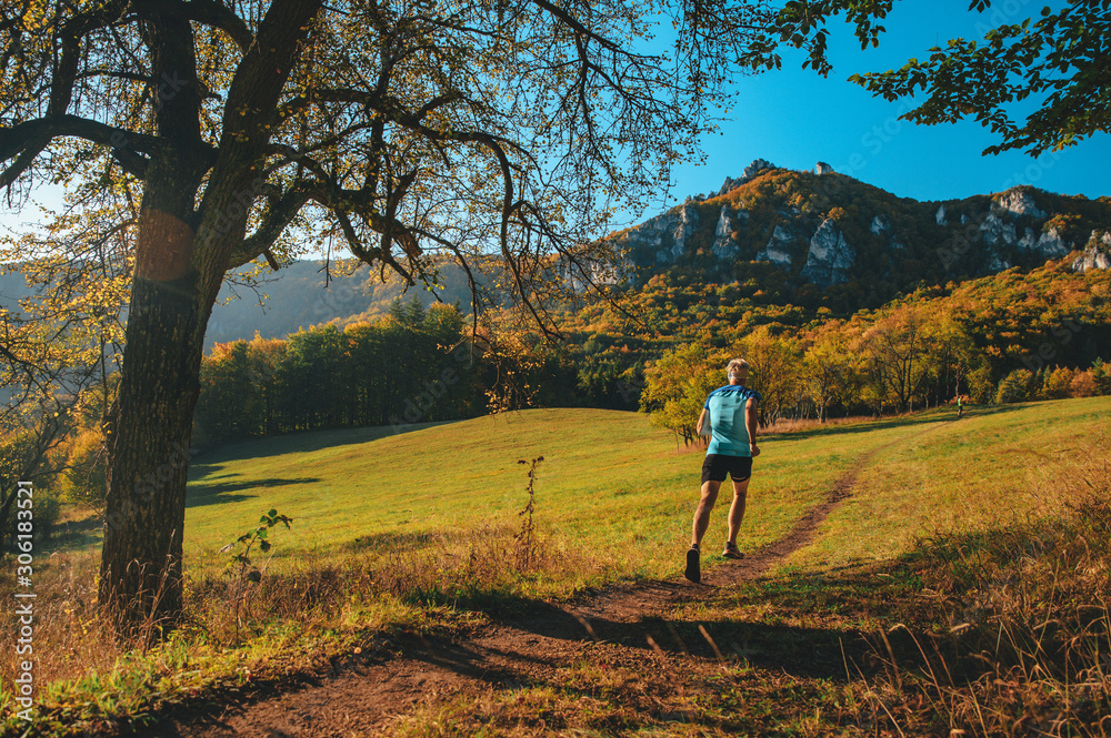 Athlete trains in warm orange sunrise light. Running in beautiful autumn nature