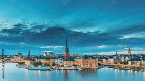 Stockholm, Sweden. Scenic View Of Stockholm Skyline At Summer Evening. Famous Popular Destination Scenic Place In Dusk Lights. Riddarholm Church In Day To Night Transition Time Lapse photo
