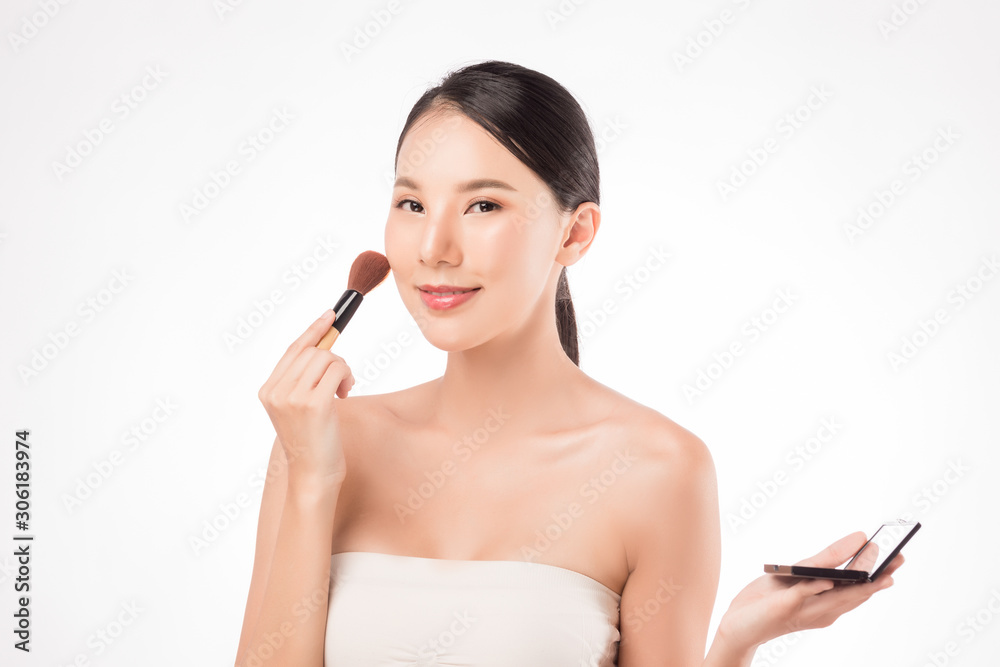 Young attractive Asian woman holding make up case and brush, applying blush on her face isolated on white. Young attractive Asian woman holding make up case and brush, applying blush on her face isolated on white.