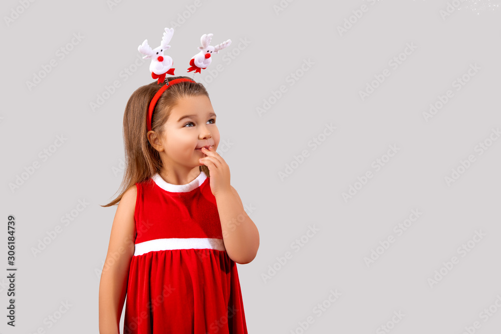 Happy girl Smiles, the child wears a red outfit. Girl wears a Christmas Santa Dress. Beautiful Kid is Laughing and posing in Studio. Little Girl at party. Isolated. gray background Happy girl Smiles, the child wears a red outfit. Girl wears a Christmas Santa Dress. Beautiful Kid is Laughing and posing in Studio. Little Girl at party. Isolated. gray background