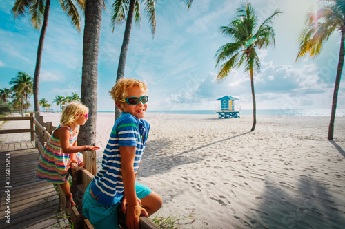 Obraz na płótnie happy boy and girl looking at tropical beach with palms