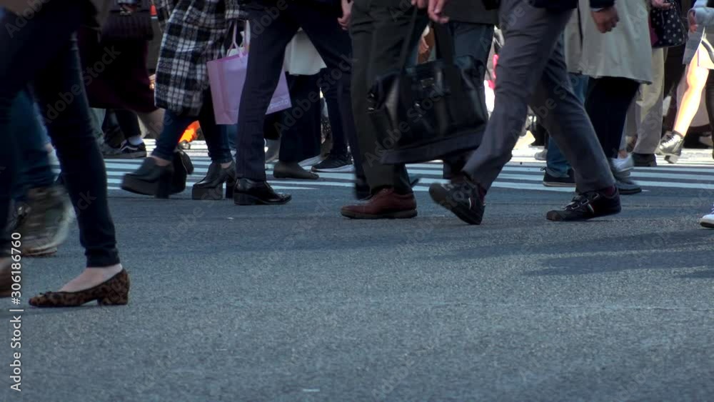 TOKYO, JAPAN - NOV 2019 : Crowd of people at Shibuya Scramble Crossing in busy early evening rush hour. Many commuters and tourists at the street. Shot in sunset time. In front focus. Slow motion. TOKYO, JAPAN - NOV 2019 : Crowd of people at Shibuya Scramble Crossing in busy early evening rush hour. Many commuters and tourists at the street. Shot in sunset time. In front focus. Slow motion.