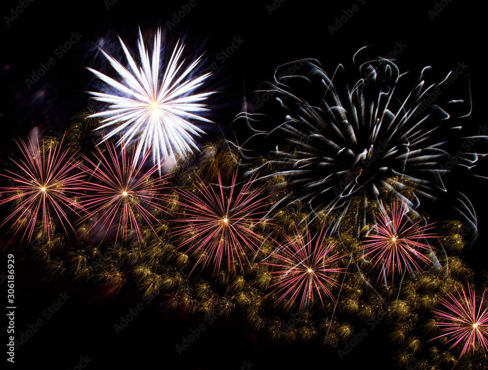 Cluster of colorful fireworks of various colors bursting against a black sky