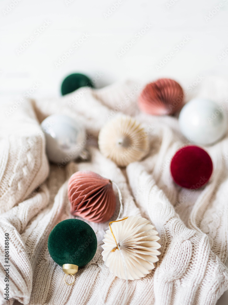 Creative cozy Christmas composition with fir tree and different Christmas balls on white knitting background.