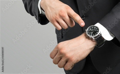 Businessman pointing at hand watch on grey background