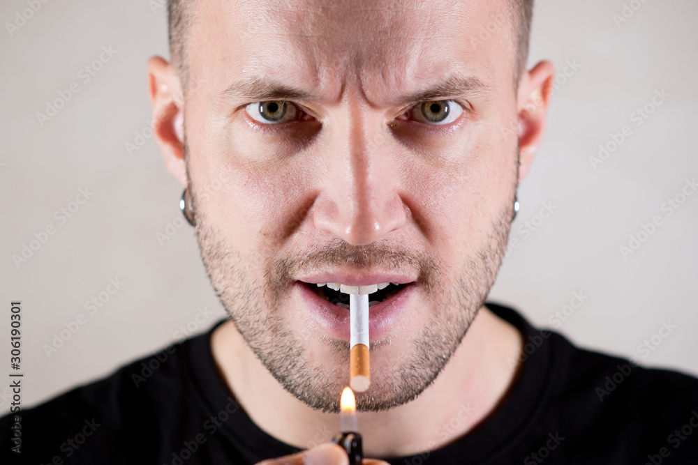 Fotografie stern man is going to light a cigarette on the wrong side