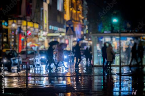 crowd of people walking on the city streets on rainy night 