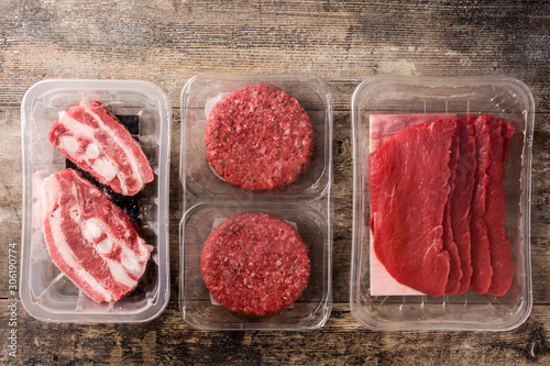 Different types of meat packaged in plastic on wooden table. Top view	