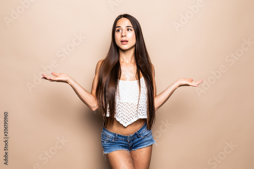 Young pretty woman with reised hands isolated on beige background