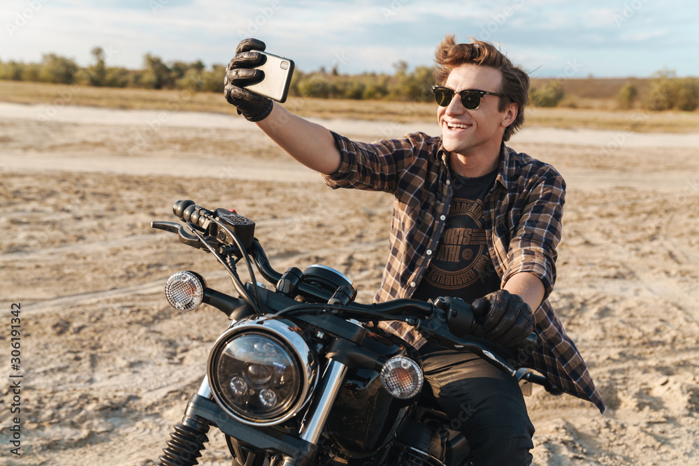 Fototapeta premium Man biker outdoors at the desert field take a selfie