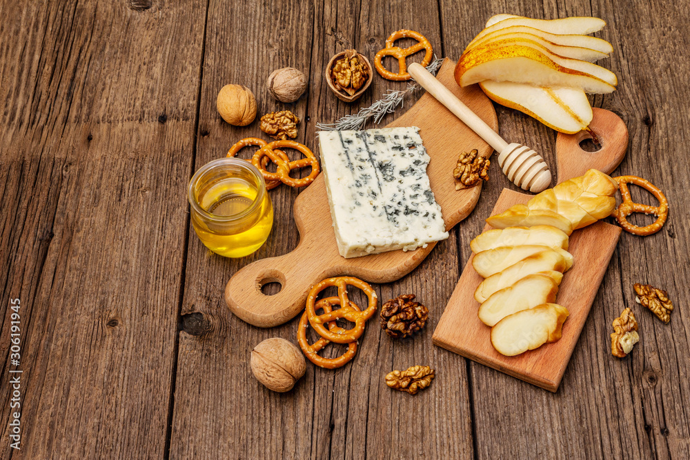 Cheese plate antipasti with smoked and blue cheese, crackers, honey, walnuts and ripe pear. Traditional snack recipe idea. Wooden boards background Cheese plate antipasti with smoked and blue cheese, crackers, honey, walnuts and ripe pear. Traditional snack recipe idea. Wooden boards background