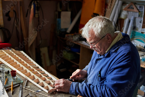 Senior man makes the wing of a radio-controlled aircraft, the construction of the airplane.