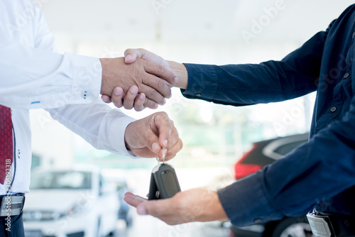 Delivering new car keys for selling cars to customers and shaking hands