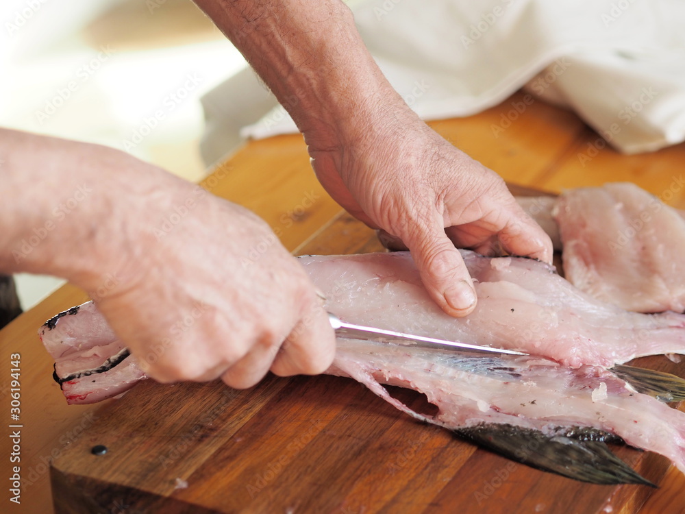 hands of a fisherman carve river fish on the table