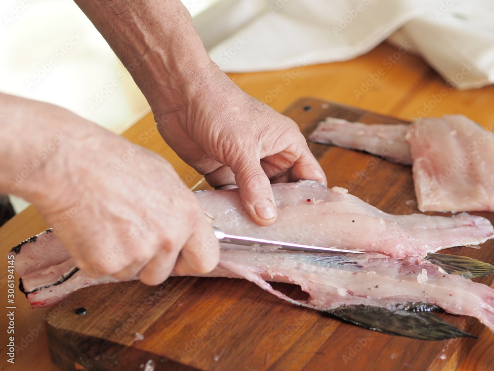 hands of a fisherman carve river fish on the table