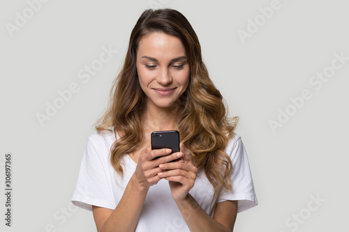 Satisfied young woman looking at screen, using cellphone apps