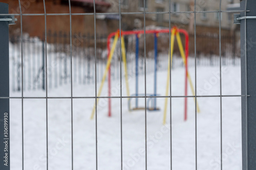 children's swing behind the fence. focus on the fence.
