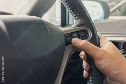 Hand pushes cruise control button on steering wheel and speed limitation.