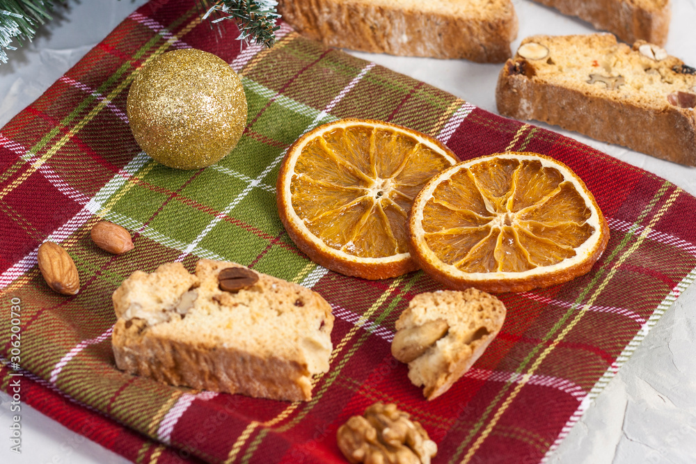 Traditional Italian Biscotti or Cantuccini cookies with hazelnuts, almonds, walnuts on a red-green napkin with slices of dried oranges. Christmas and New Year's baking.