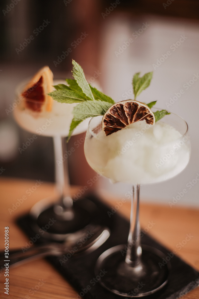 Two gin based sorbet cocktails on a black slate with tea spoon. Concept of refreshing cocktails and alcoholic drinks. Selective focus on the glasses. - obrazy, fototapety, plakaty 