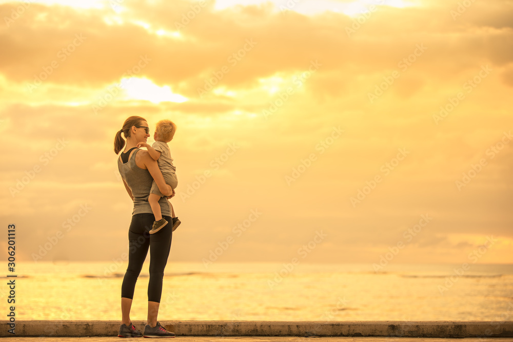 Mother and her child watching the sunset together. Happy mother son moment. 