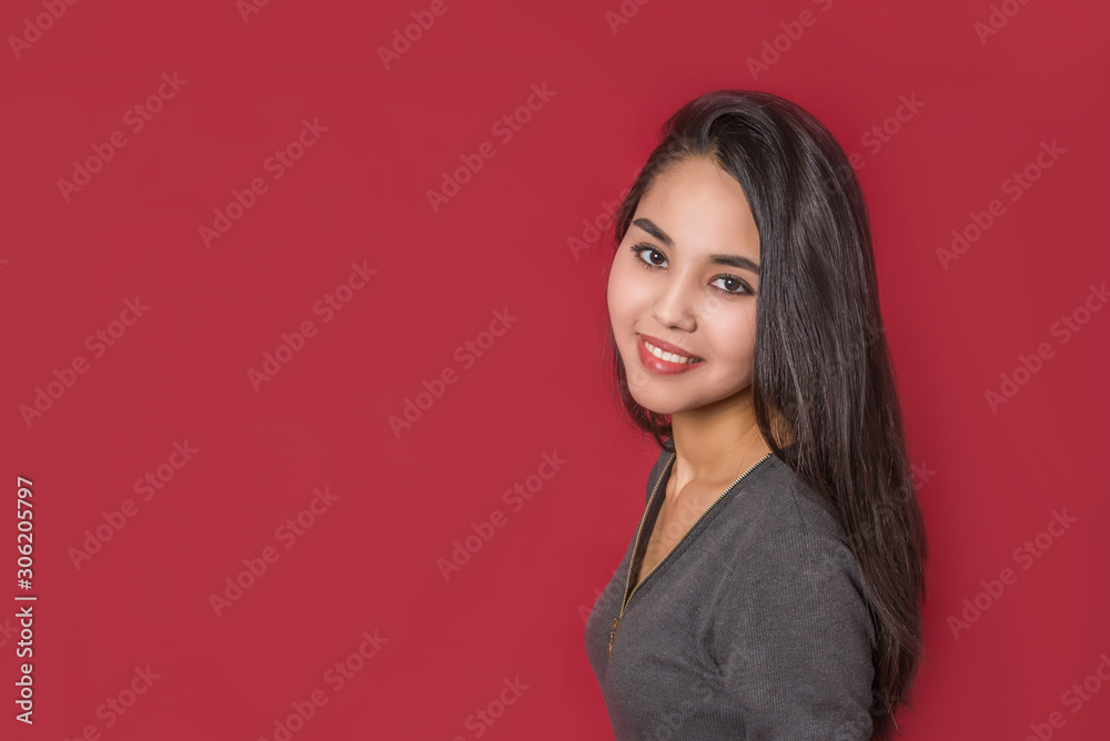 Obraz premium young attractive girl with long black hair on red background in Studio. the girl on the casting. classic portrait copy space