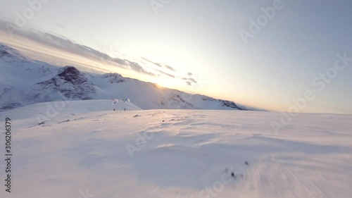Aerial FPV footage of paragliders in mountain.