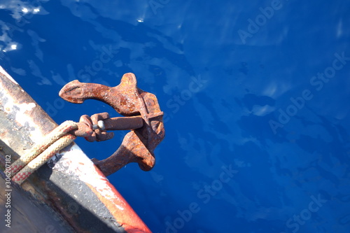 Anchor of a ship over a blue body of water.