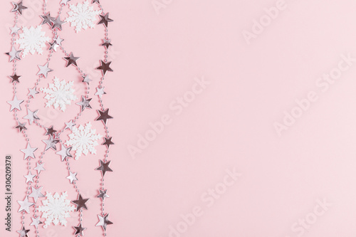 Christmas composition. Frame made of balls and snowflakes on pastel pink background.