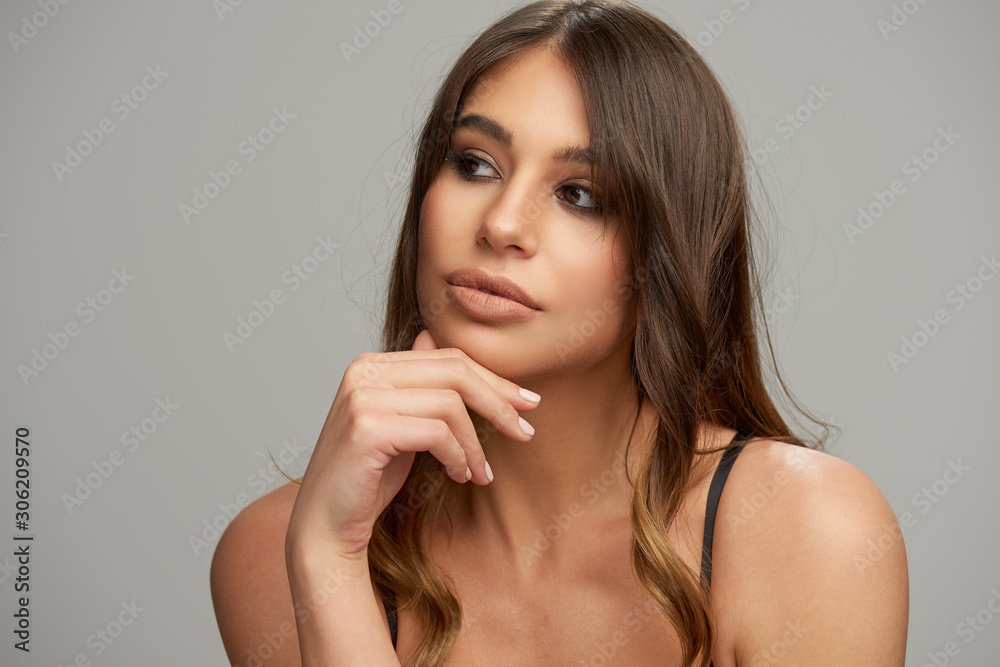 Headshot of beautiful Caucasian brunette posing in front of grey background. Beauty photography. Headshot of beautiful Caucasian brunette posing in front of grey background. Beauty photography.