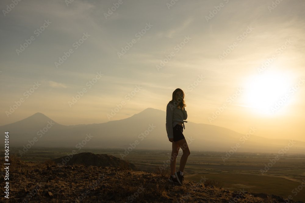 Beautiful and slender Girl travels in Armenia, Yerevan. At sunset, she jump silhouettes against the backdrop of Mount Ararat. Very beautiful landscape